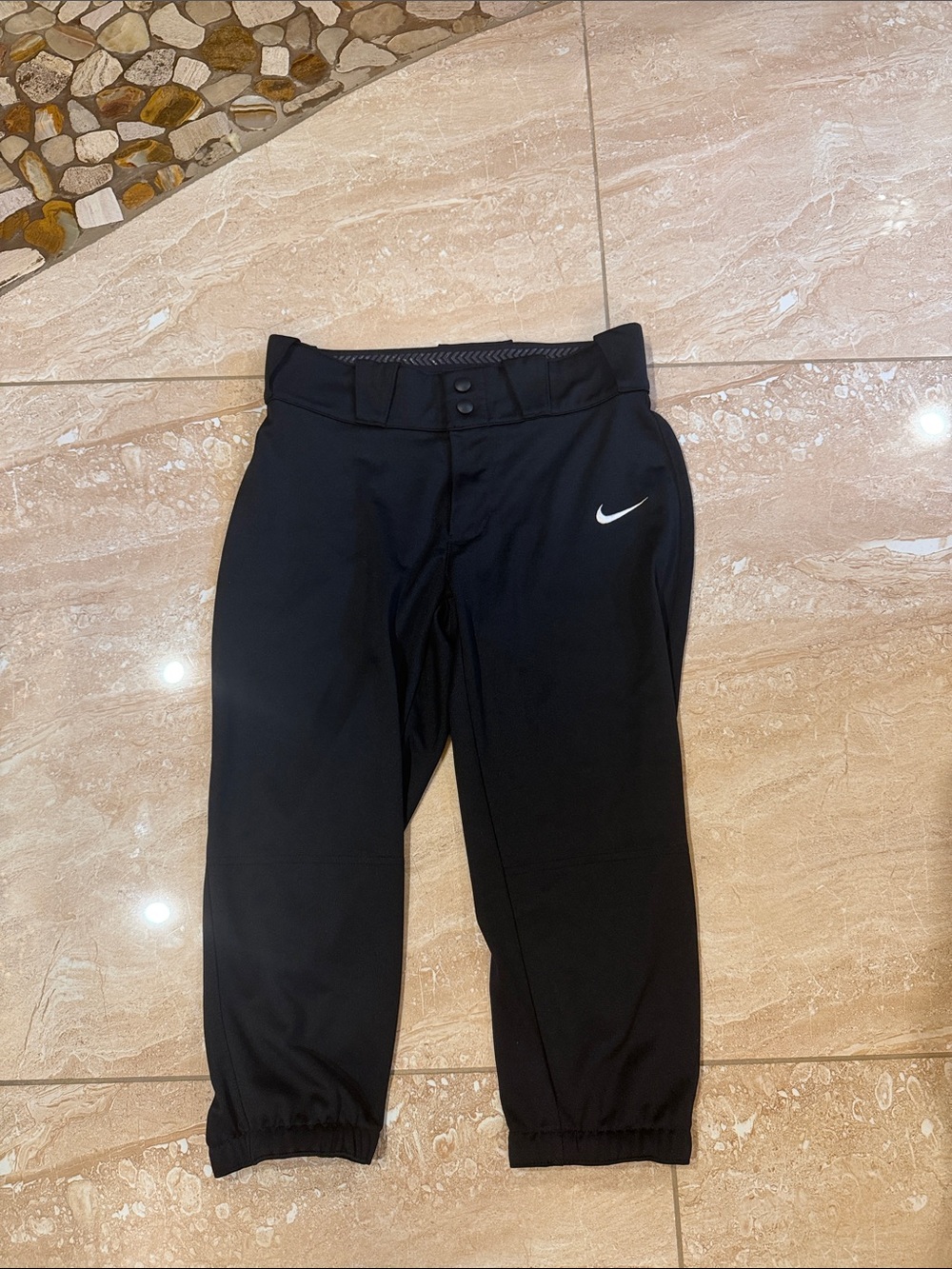 Nike Vapor Select softball pants feature a black design with a white swoosh logo